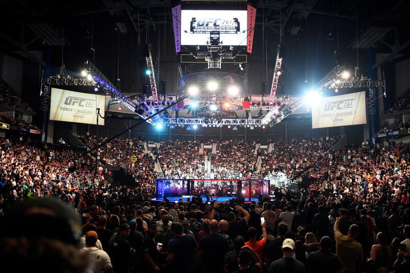 A packed UFC arena with the Octagon under lights.